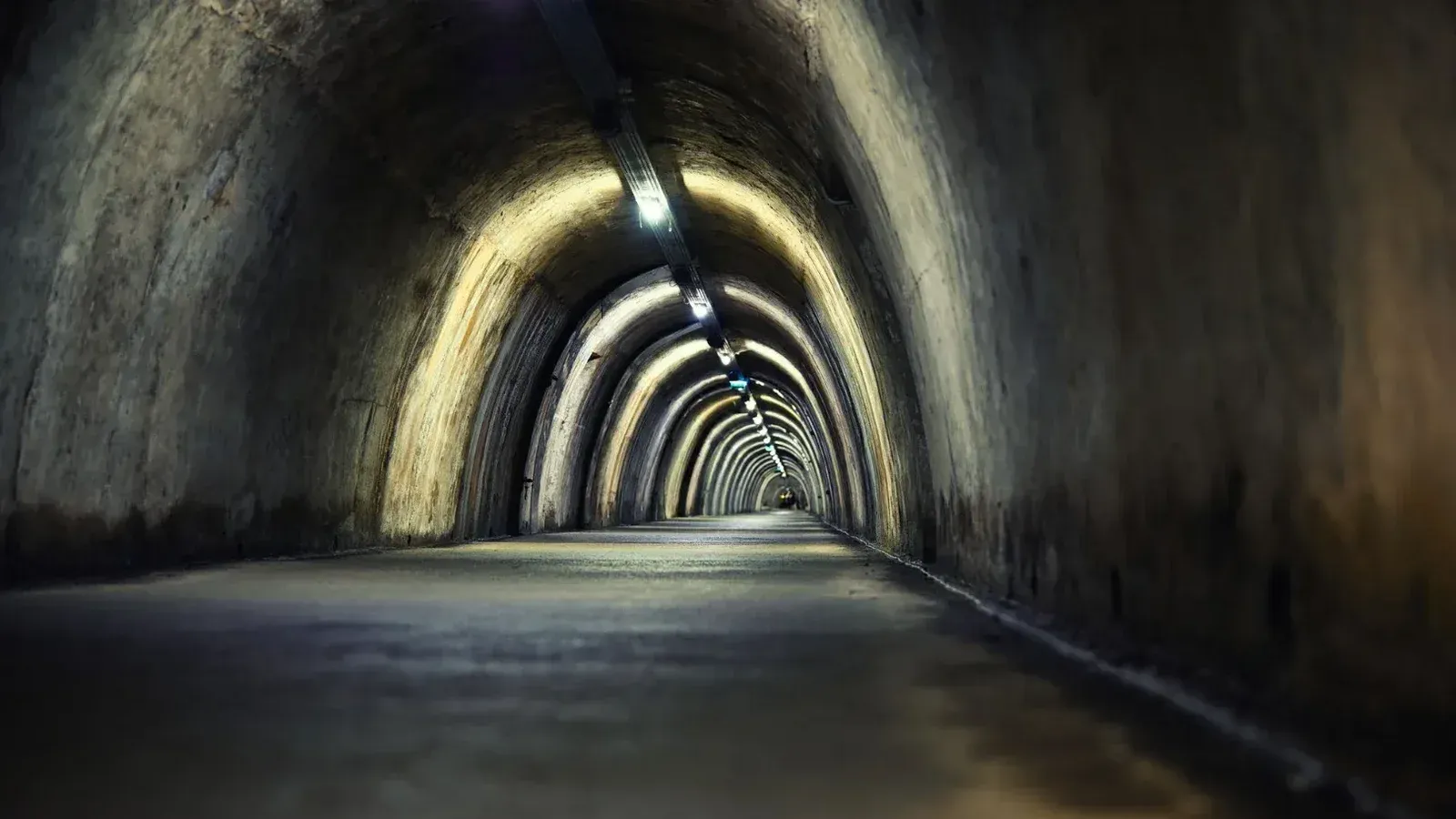 Misterioso túnel subterráneo con luces arqueadas creando una atmósfera de mal humor.