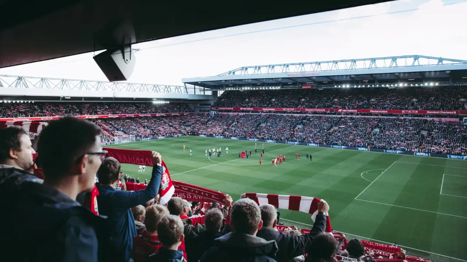 Fans cheer as players take the field at a vibrant football stadium, creating an electric atmosphere.