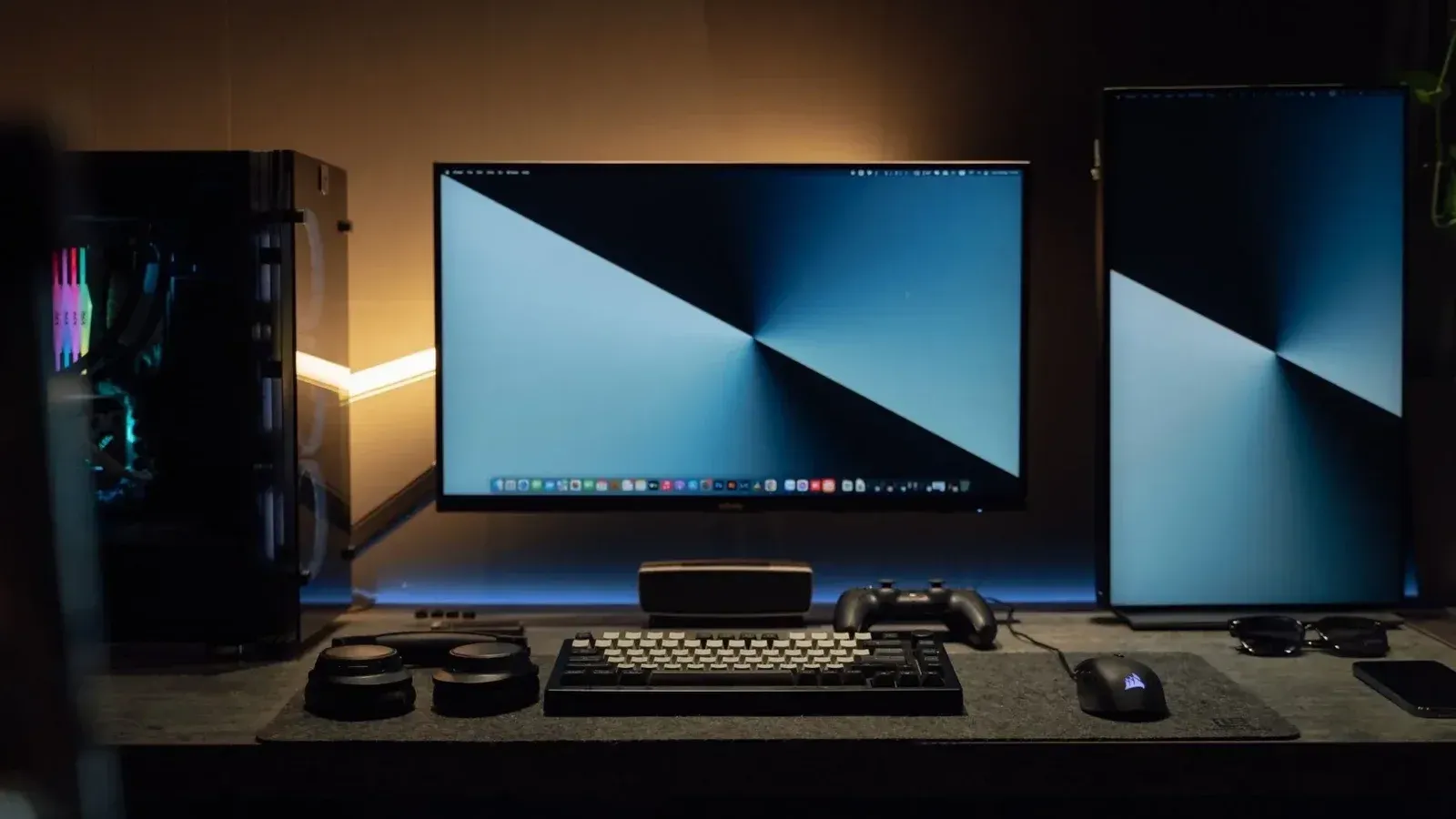 Una configuración de escritorio de computadora moderna con poca luz con monitores duales, un teclado y accesorios para juegos.