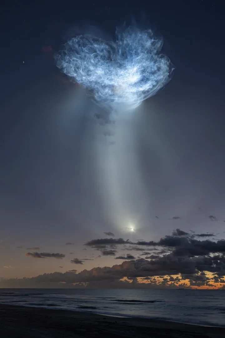 Los penachos de escape de un cohete SpaceX Falcon 9 que transporta la nave espacial Dragon de la compañía se ven iluminados por la luz del sol contra el cielo antes del amanecer.