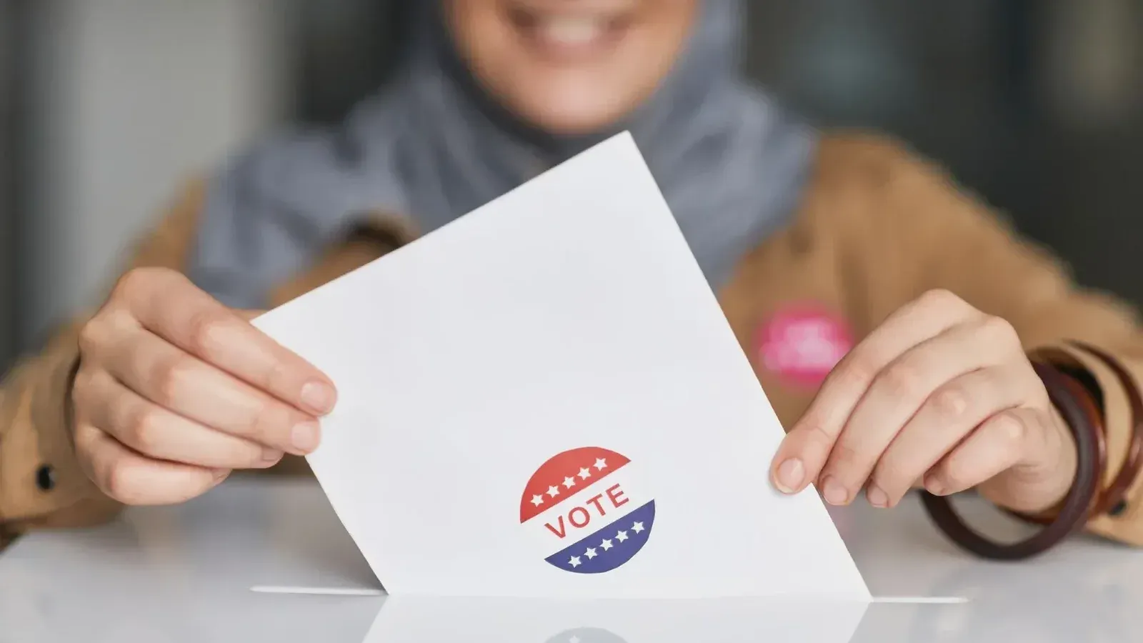 Close-up of hands holding a vote ballot, symbolizing election participation.