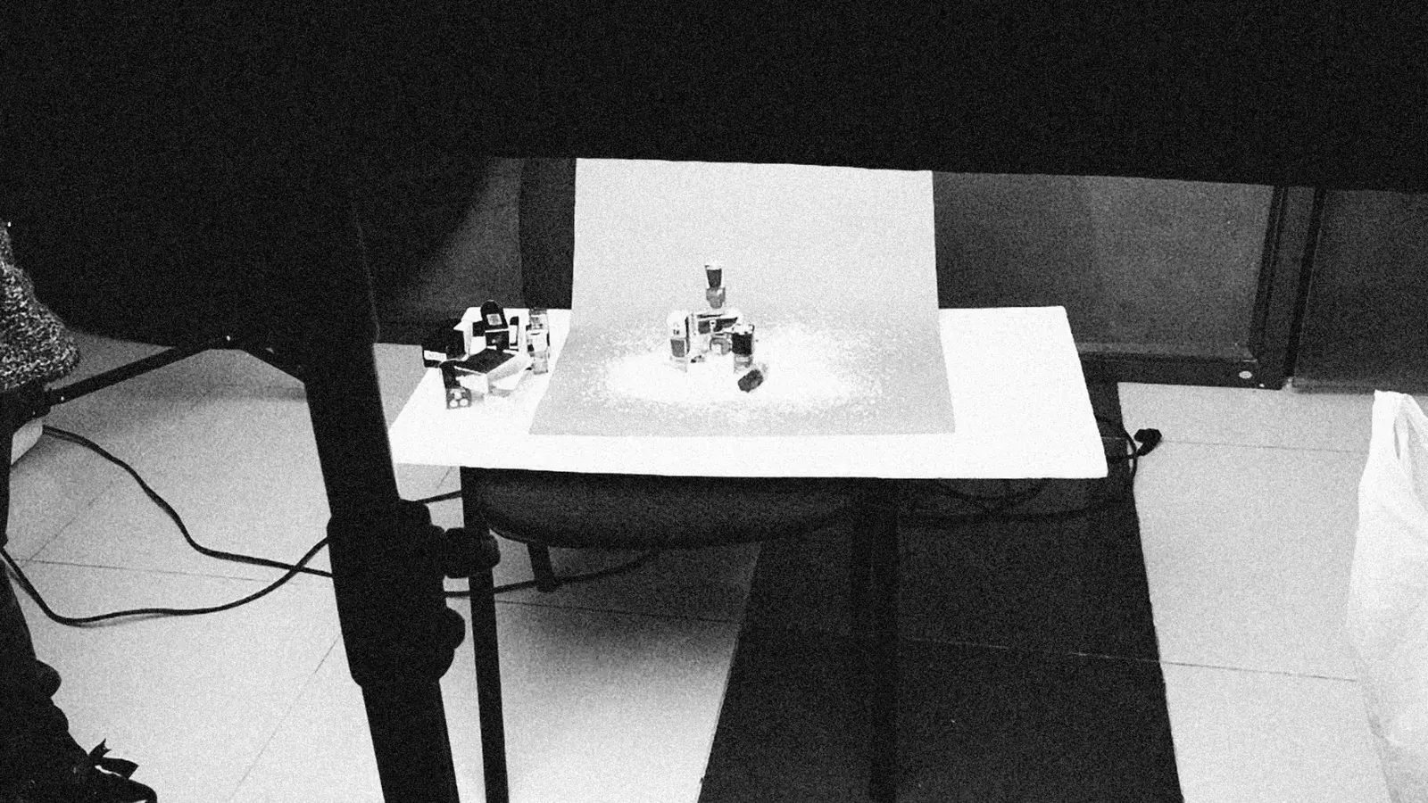 Configuración de estudio en blanco y negro con cosméticos en la mesa para sesión de fotos del producto.