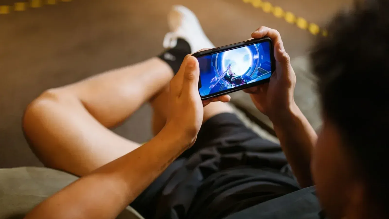Man playing a video game on a smartphone while sitting comfortably indoors.