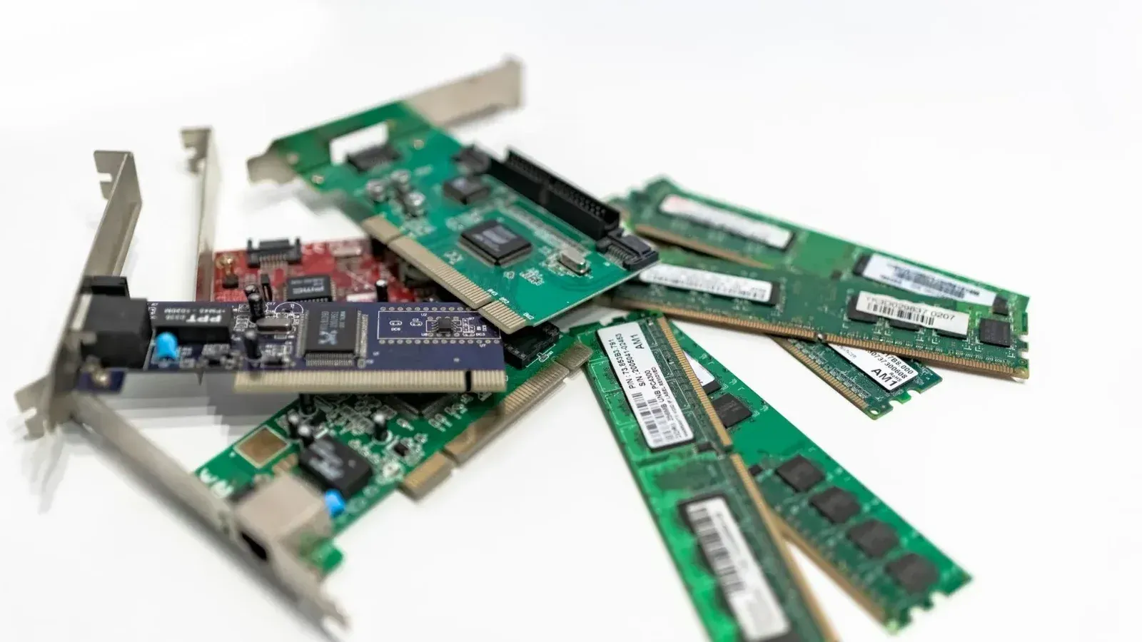 A detailed close-up of computer RAM sticks and PCI cards arranged on a white surface for tech illustration.