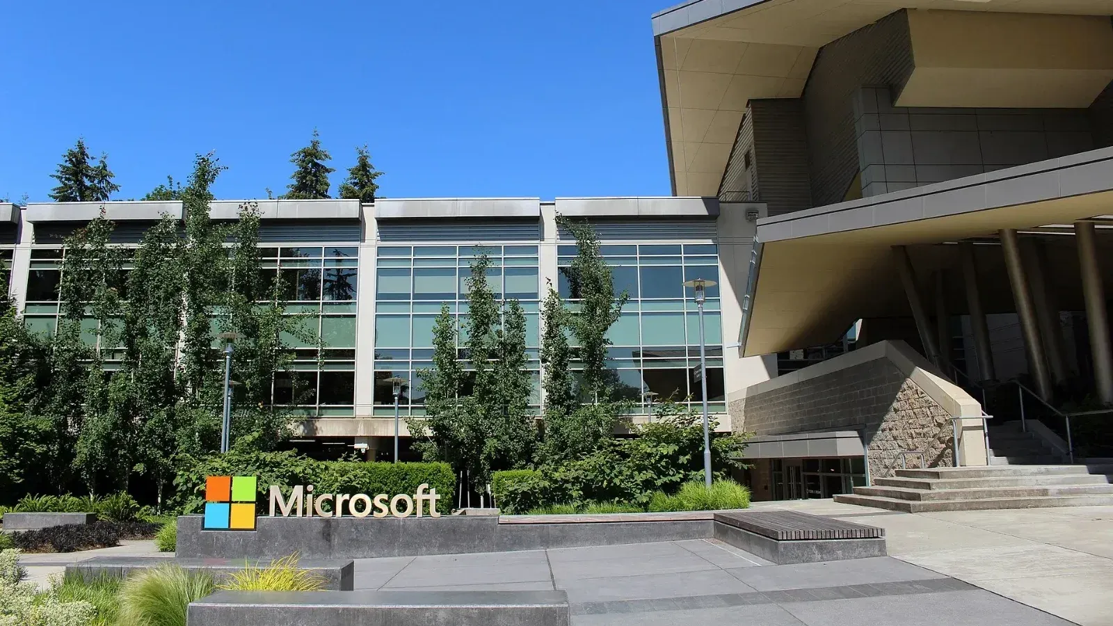 Edificio 92 del campus de Microsoft en Redmond, Washington, con el logotipo y el nombre de Microsoft en un muro bajo frente a la fachada de cristal