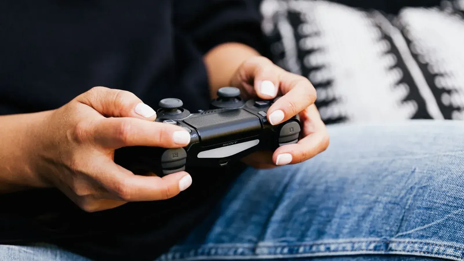 Una persona que juega videojuegos con un primer plano de sus manos sosteniendo un controlador de juegos.