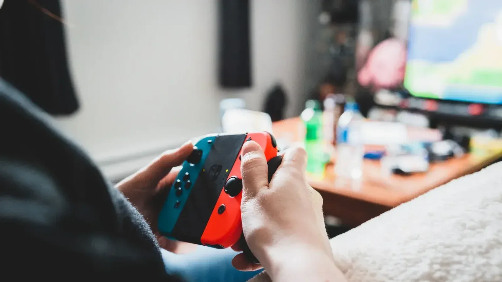 Crop unrecognizable person using console in hands while playing videogame on blurred background
