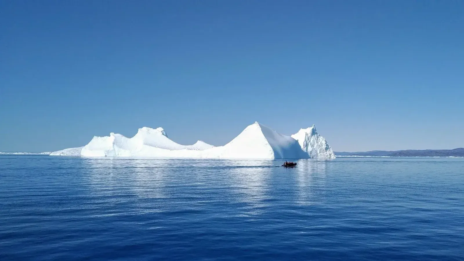 Una serena escena de un iceberg con un pequeño bote en las aguas de Ilulissat, Groenlandia.