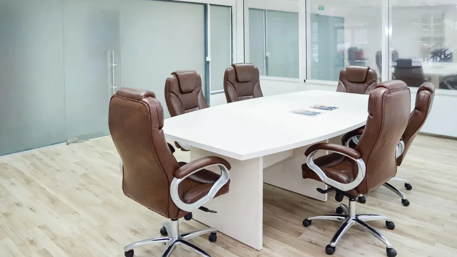 Amplia sala de conferencias con diseño moderno, con sillas de cuero y una mesa blanca.