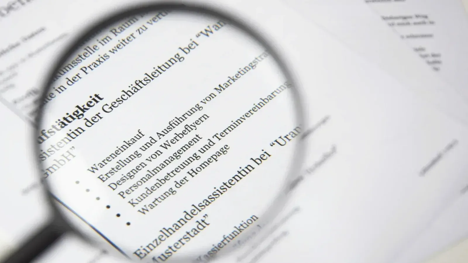 Primer plano de un texto de documento de negocios bajo una lupa.