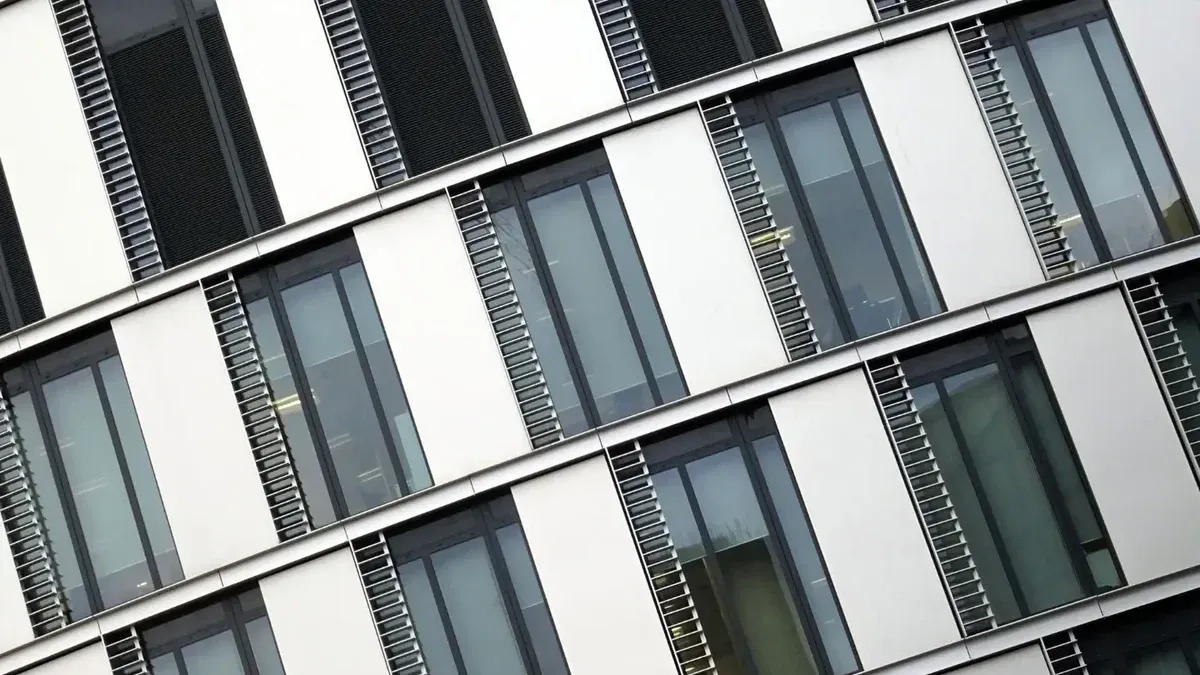 Vista en ángulo de un moderno edificio de oficinas con grandes ventanas de vidrio y detalles de acero.