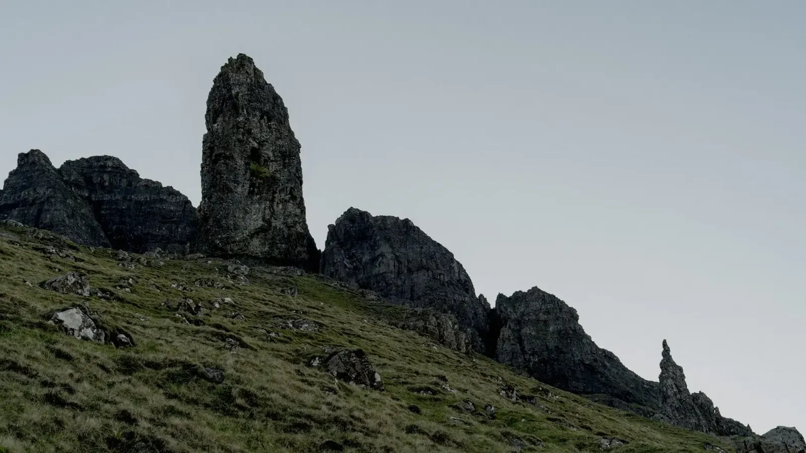 Las dramáticas formaciones rocosas se elevan contra un suave cielo gris en un paisaje montañoso escarpado.