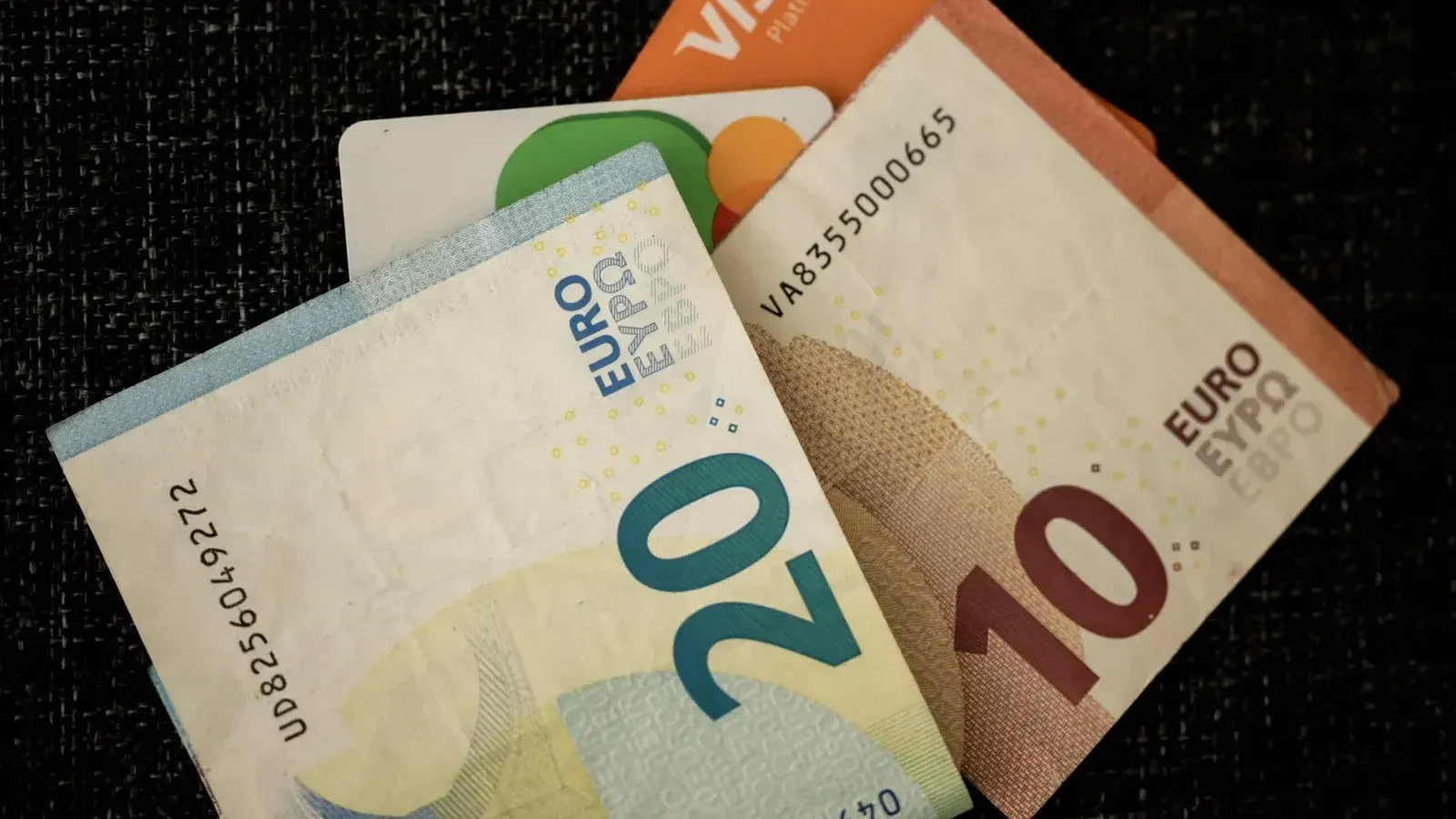 Close-up de billetes en euros y tarjetas de crédito en una superficie de textura oscura.