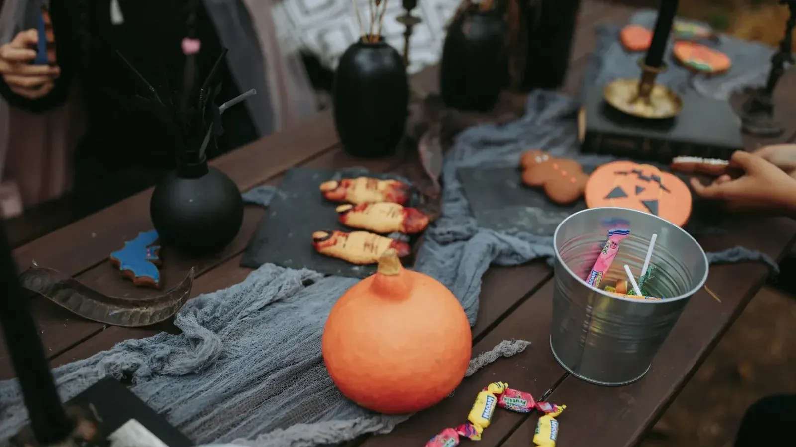 Mesa rústica de Halloween con golosinas, calabaza, dulces y decoraciones espeluznantes.