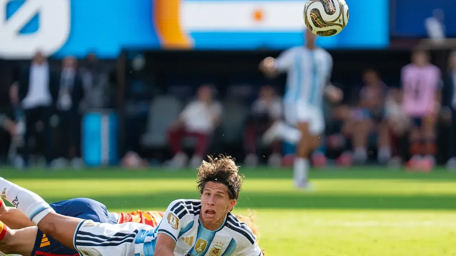 Giuliano Simeone, con la camiseta de Argentina, cae tendido sobre el césped mientras sigue con la mirada el balón en el aire.