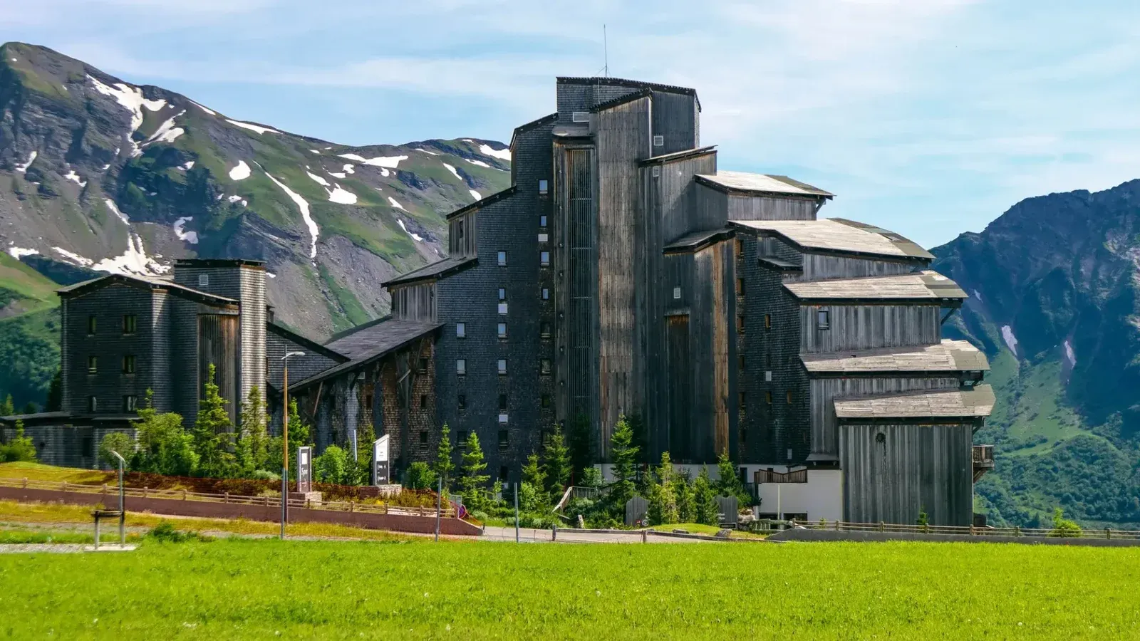 Edificio de resort de madera distintivo contra un impresionante telón de fondo de montaña en el entorno rural.