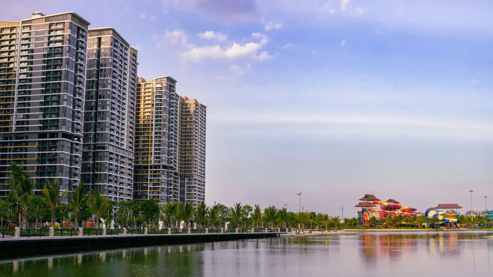 Una vista panorámica de los rascacielos urbanos junto a un tranquilo lago al atardecer.