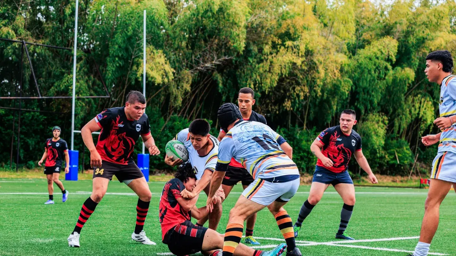 Juego de rugby lleno de acción con jugadores que abordan un campo verde.