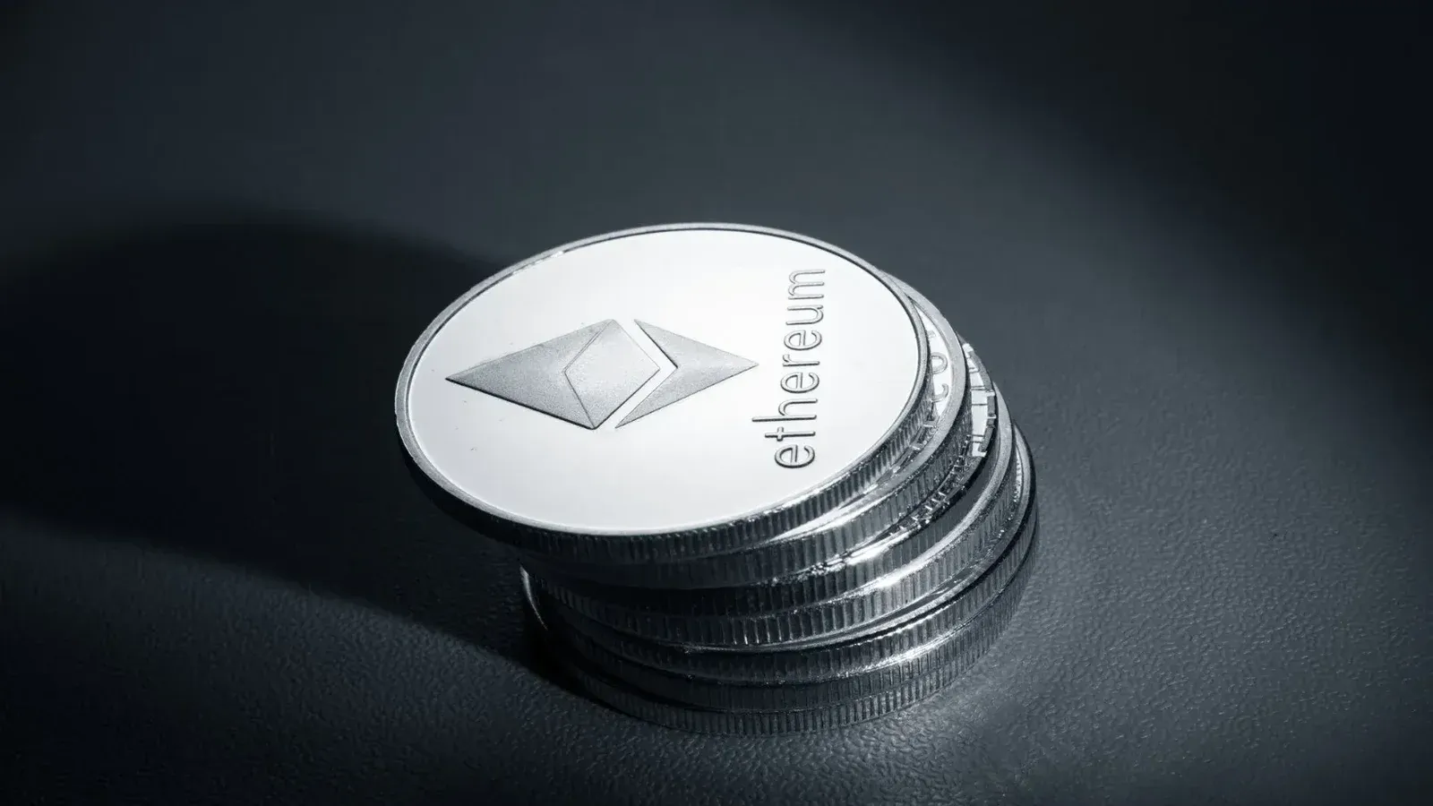 Close-up of stacked Ethereum coins on a dark textured surface, symbolizing modern cryptocurrency.