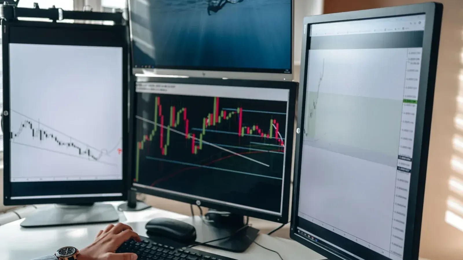 Una configuración de negociación de acciones de varios monitores que muestra gráficos y análisis de datos en un entorno de oficina en el hogar.