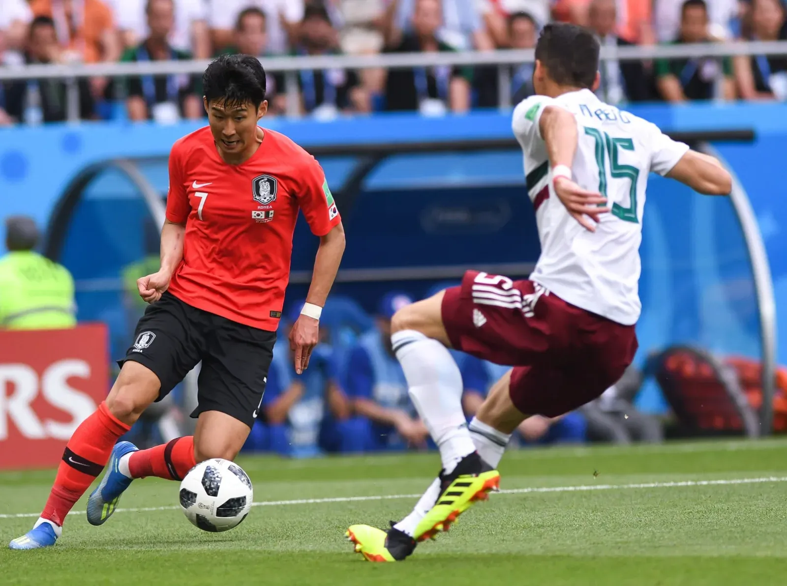 Son Heung-min, con la camiseta roja de Corea del Sur, conduce el balón ante Héctor Moreno, de México, en un partido del Mundial 2018.