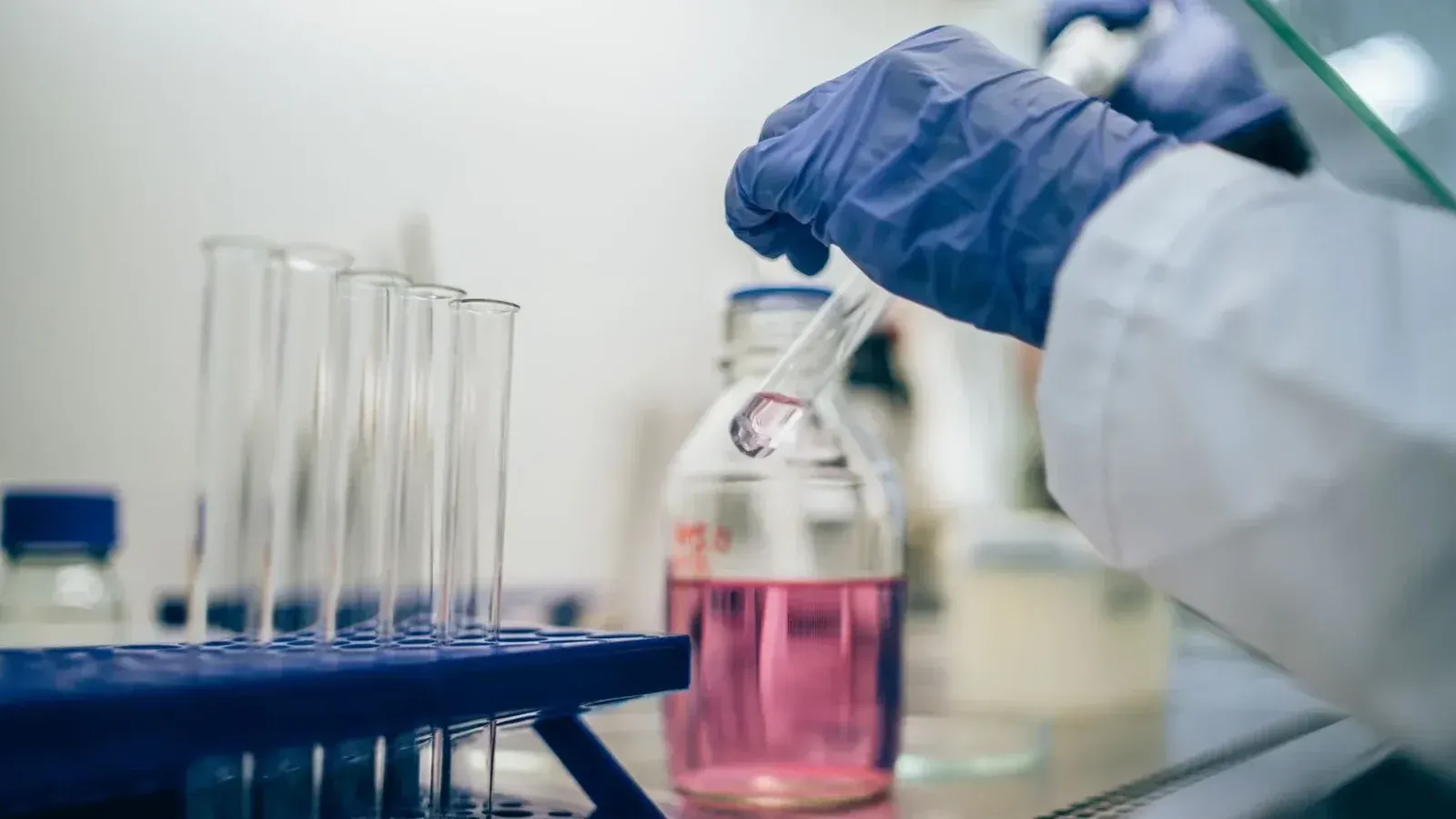 Científico en tubo de ensayo de manipulación de laboratorio con líquido rosa para investigación científica.