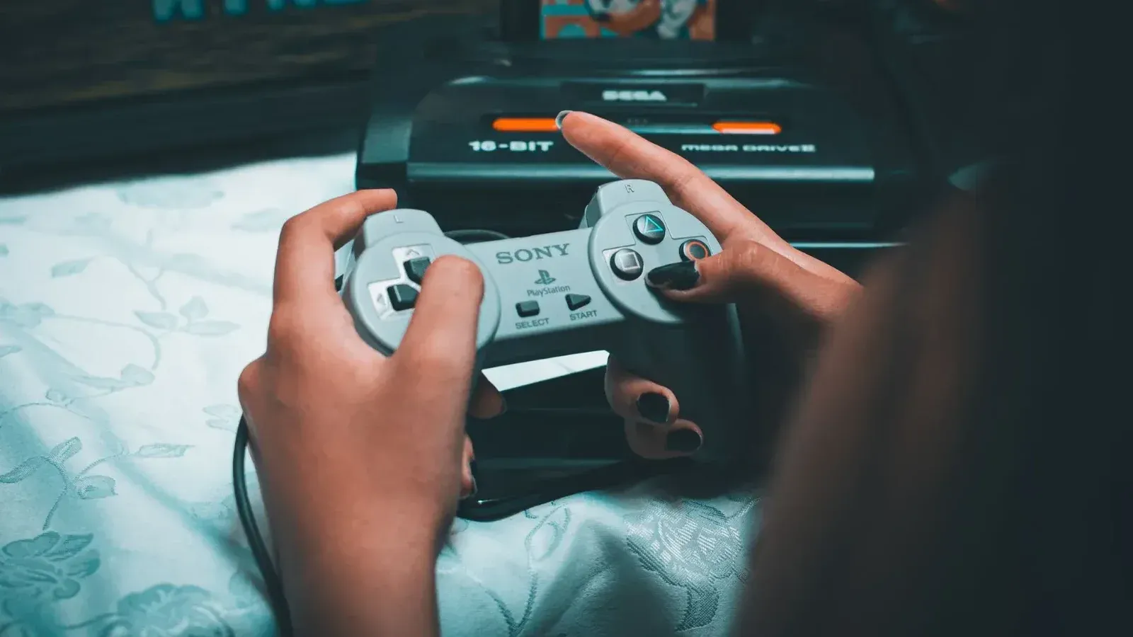 Close-up de manos sosteniendo el controlador Sony vintage con sega mega drive en segundo plano.