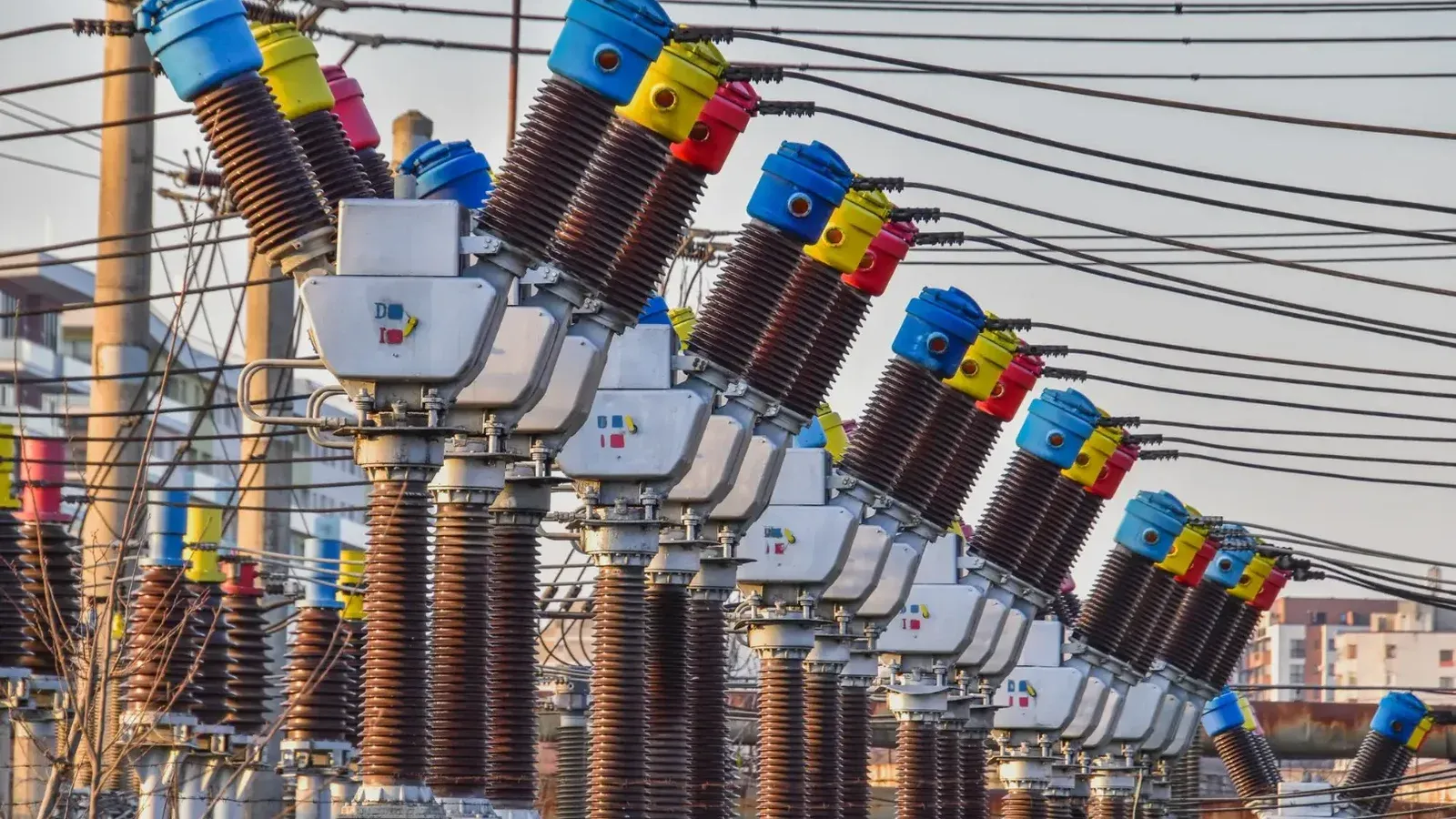 Múltiples transformadores eléctricos coloridos en una central eléctrica al aire libre bajo la luz del día.