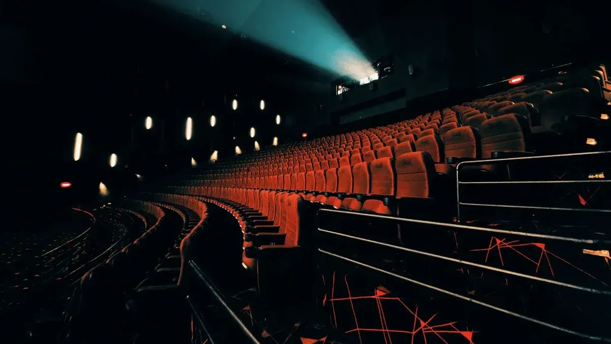 Teatro oscuro y vacío con espectacular iluminación de asientos y viga de proyector.