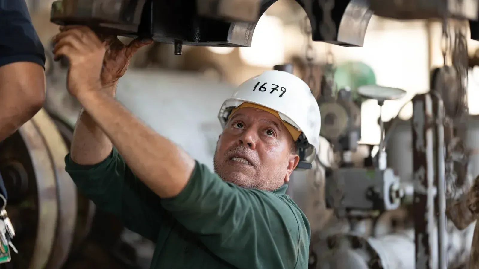 Engineer examines heavy machinery in an industrial site, showcasing technical expertise.