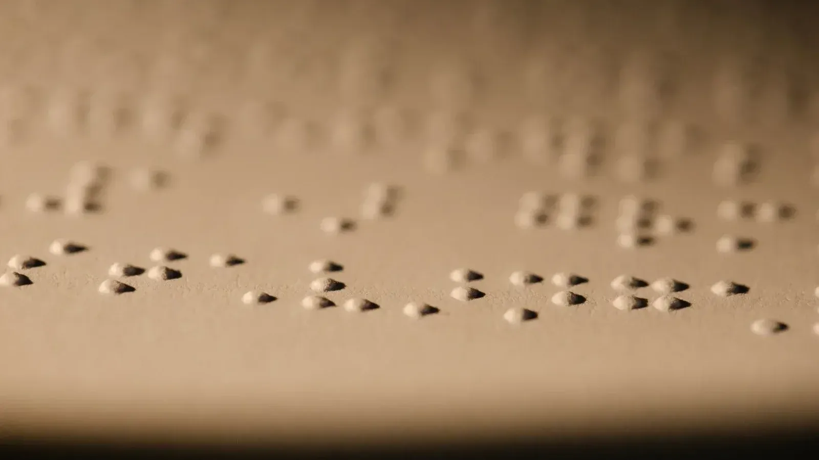 Toma macro de puntos braille en relieve en papel, ilustrando la lectura táctil para personas con discapacidad visual.