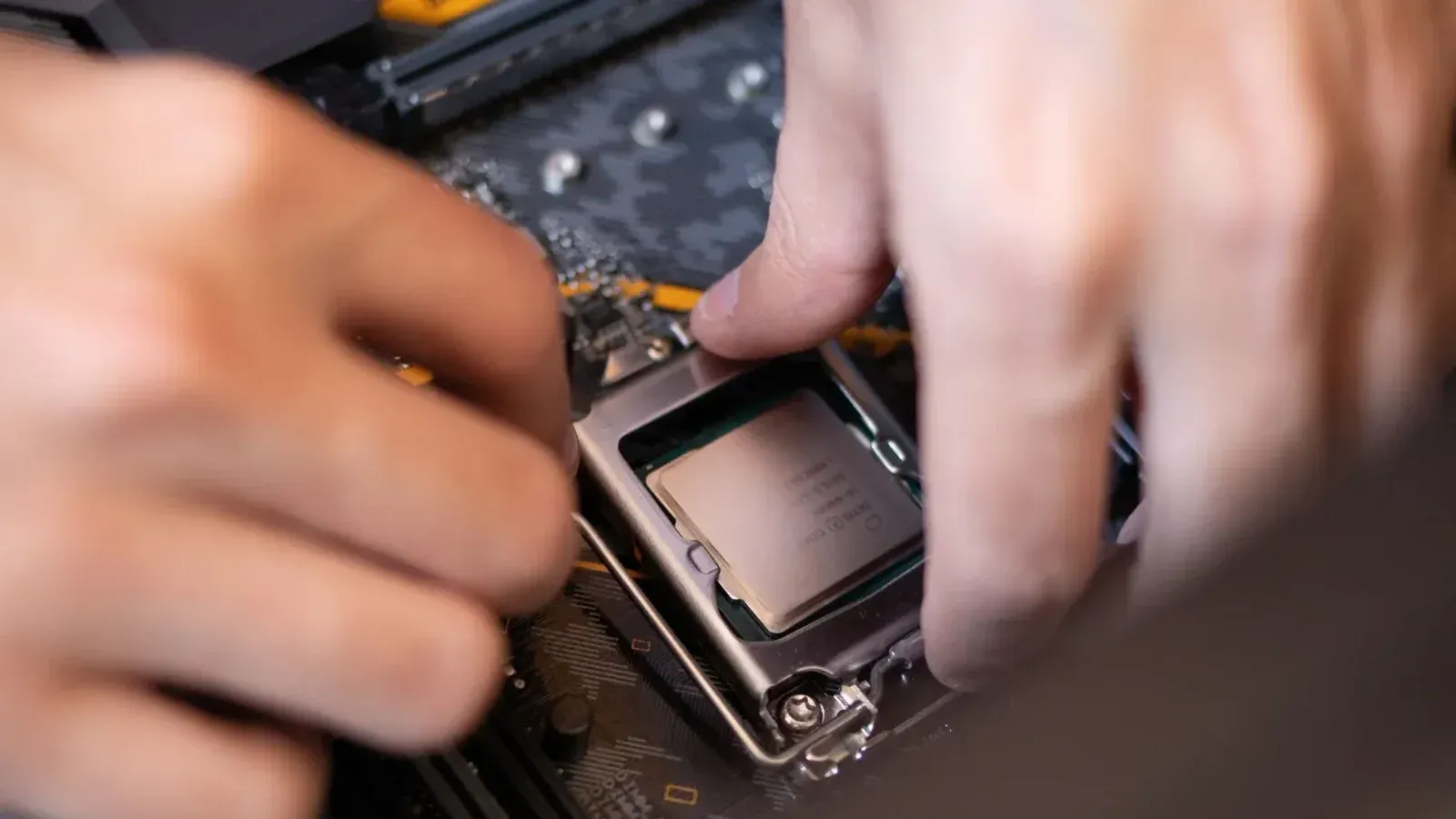 Vista detallada de manos instalando una CPU en una placa base dentro de una configuración de computadora.