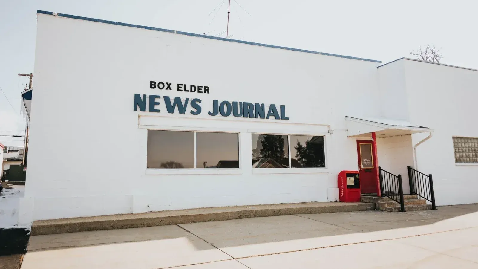 Vista exterior del edificio de diario de noticias de caja con puerta roja y signo.