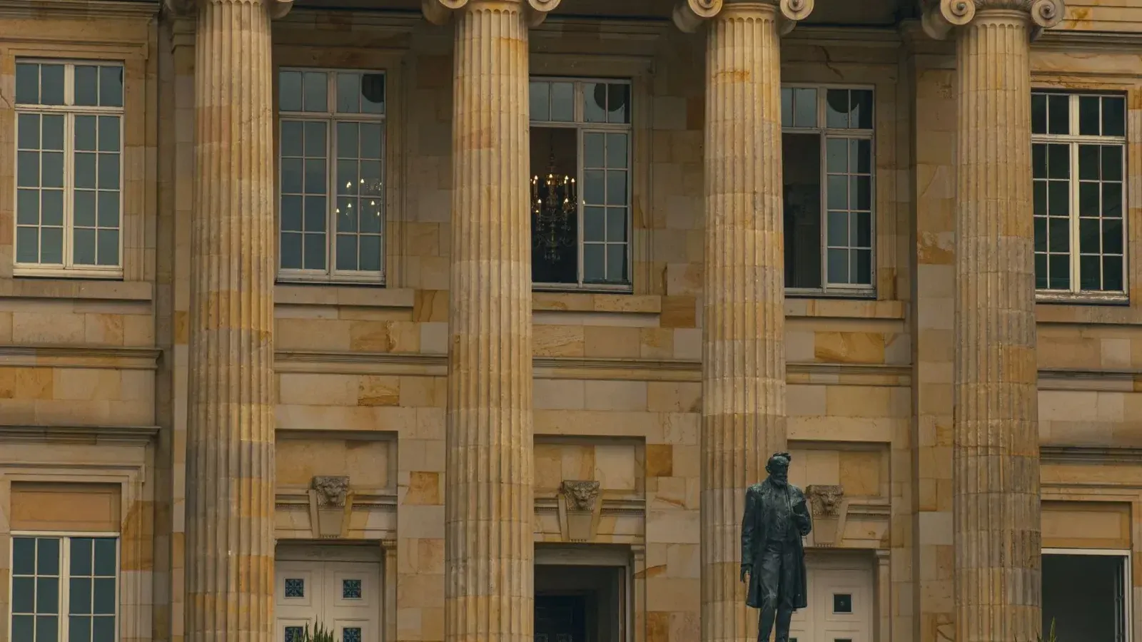 Vista elegante de un edificio clásico con pilares y una estatua en la entrada.