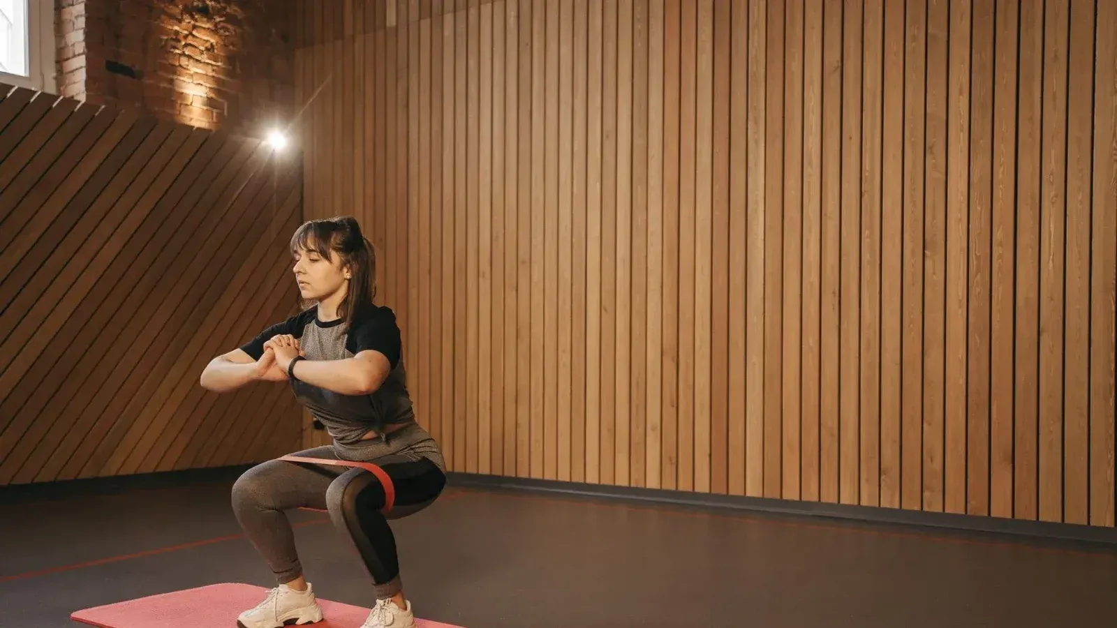 Young woman exercises indoors with resistance band on mat for fitness