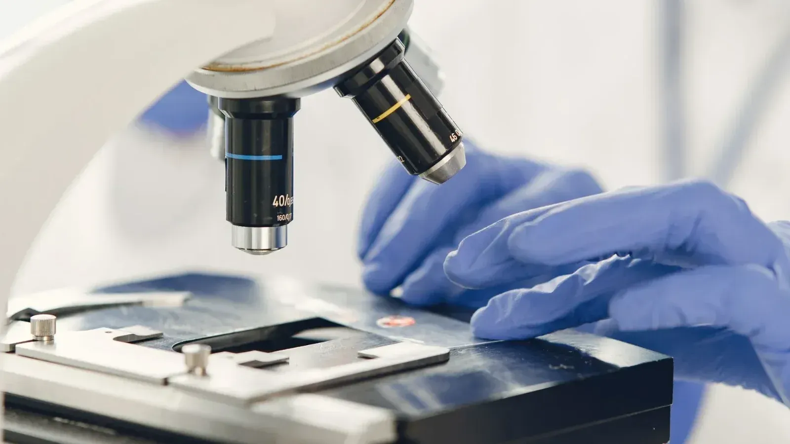 Vista cercana de un científico examinando una muestra bajo un microscopio en un laboratorio.