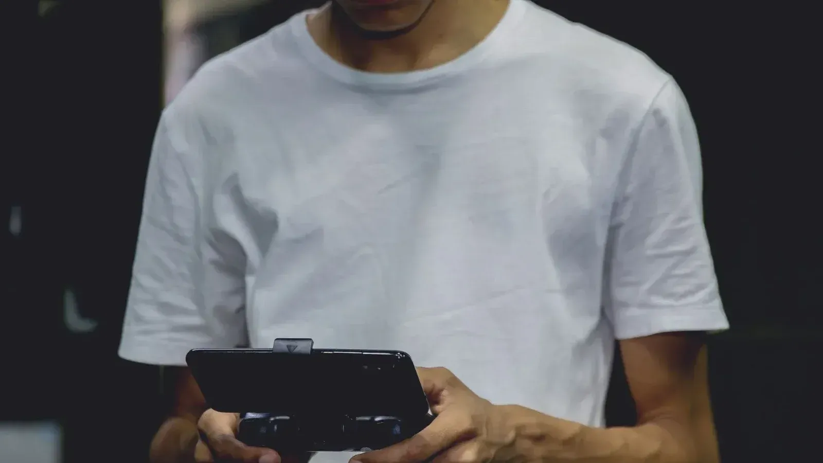 Un joven con una camisa blanca con un controlador de juego de smartphone en el interior.