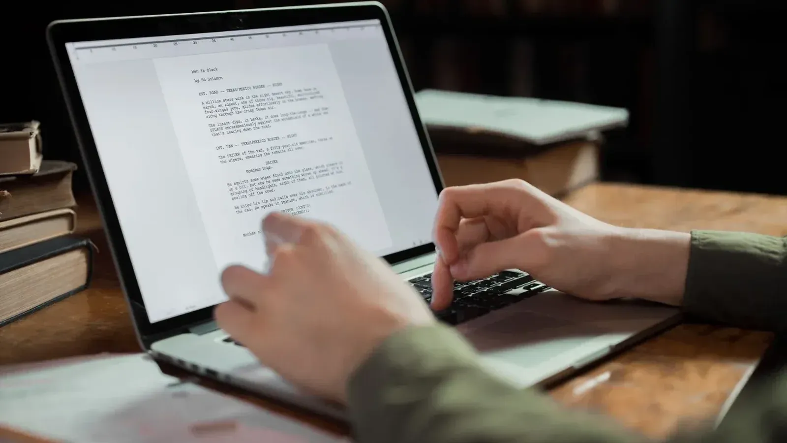 A person typing on a laptop in a cozy workspace with books around. Perfect for writing and technology themes.