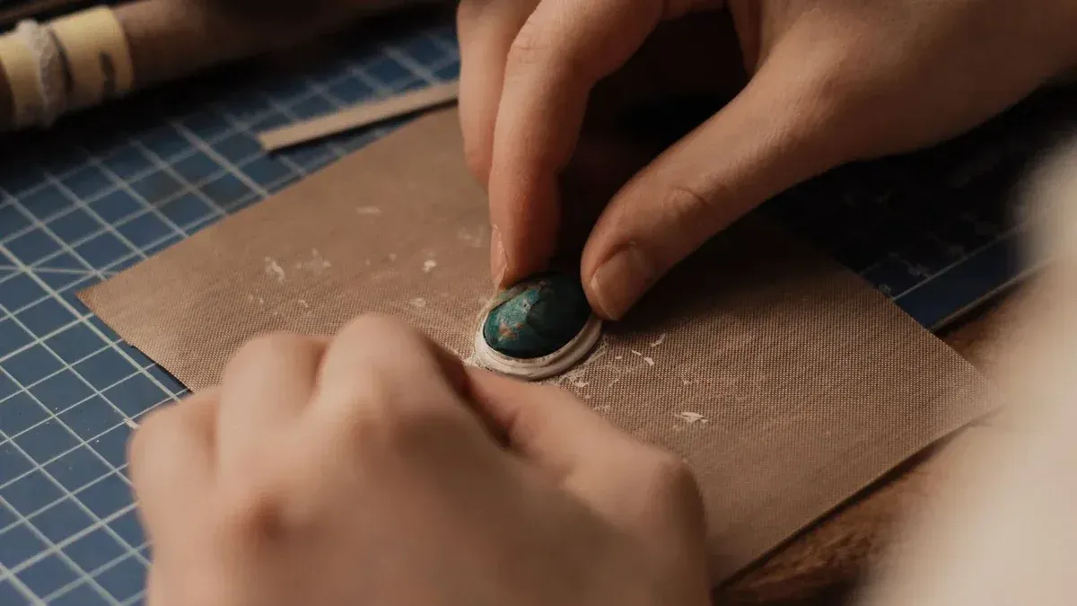 Vista detallada de las manos de joyería con piedras preciosas turquesas, enfatizando la precisión y el arte.