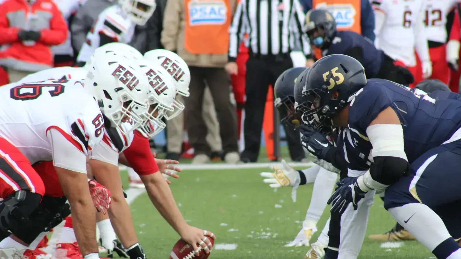 Rival football teams face off at the start of an action-packed game on the field.