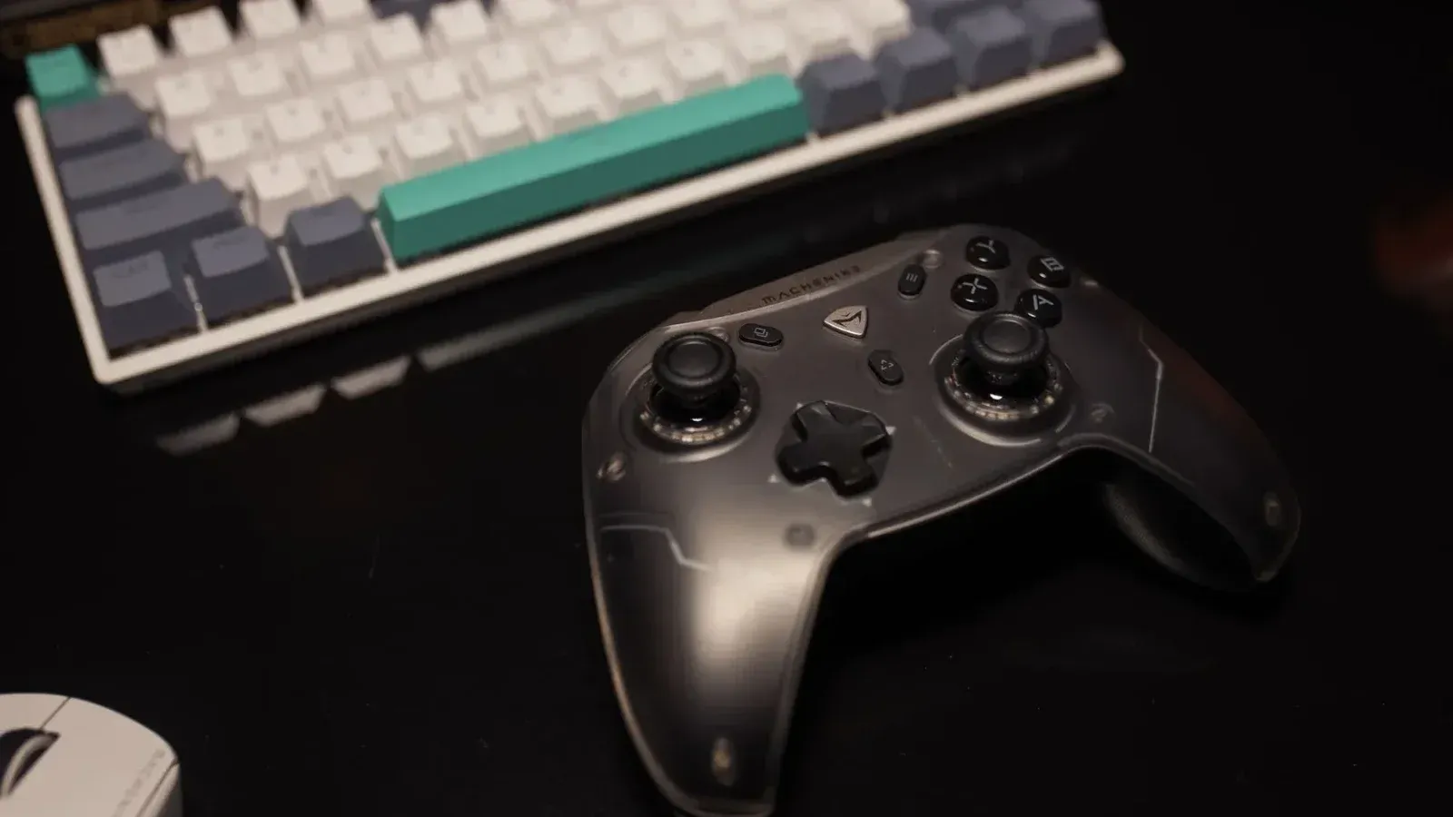 Primer plano de un controlador de juegos en un escritorio con teclado y mouse, perfecto para los jugadores.