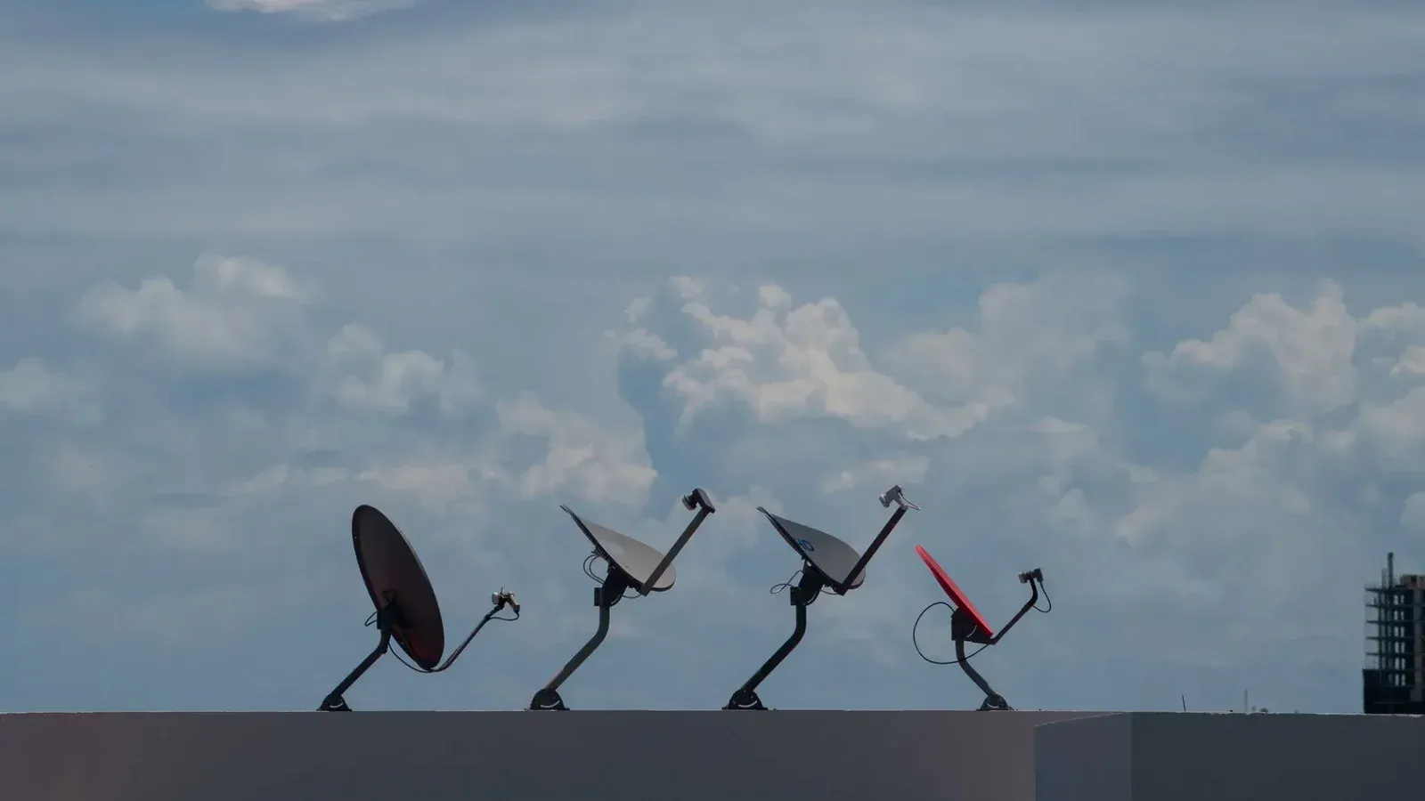 Cuatro antenas parabólicas en una azotea contra un cielo nublado en Cancún, México.