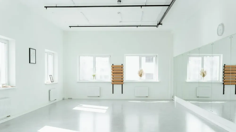 Estudio de baile brillante y vacío con espejos y luz solar en streaming.