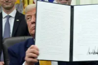 President Donald Trump holds up a signed executive order about quantum computing, in the Oval Office of the White House, Monday, June 22, 2026, in Washington. (AP Photo/Jacquelyn Martin)