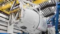 Low angle of unrecognizable technicians inspecting detail of new rocket booster at industrial space factory