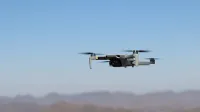 Drone flying over a desert landscape under clear blue skies.
