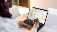 A woman making an online purchase using a laptop and credit card at home.