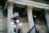 An elegant view of classic architectural columns with an antique street lamp, ideal for urban landscapes.