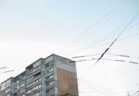 Cityscape view of an apartment building and power lines under a clear blue sky.