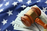 Close-up of a gavel on US dollar bills with American flag backdrop symbolizing justice and finance.